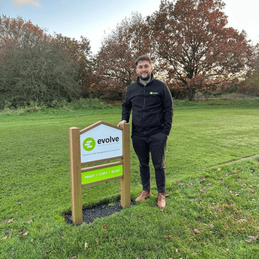 Jack Wiles outside Evolves sponsor signage at Diss Golf Club