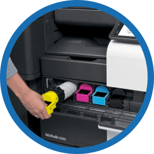 Ink cartridges being removed from a Konica Minolta device. Our services include replenishment of ink cartridges and toner.